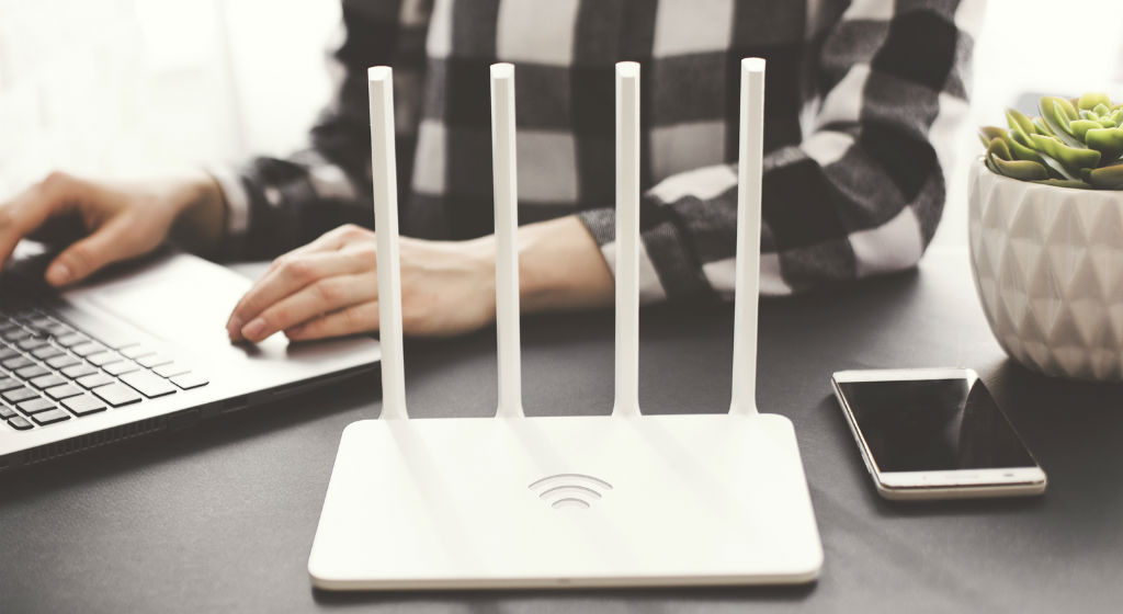 girl-works-at-laptop-with-router-on-table